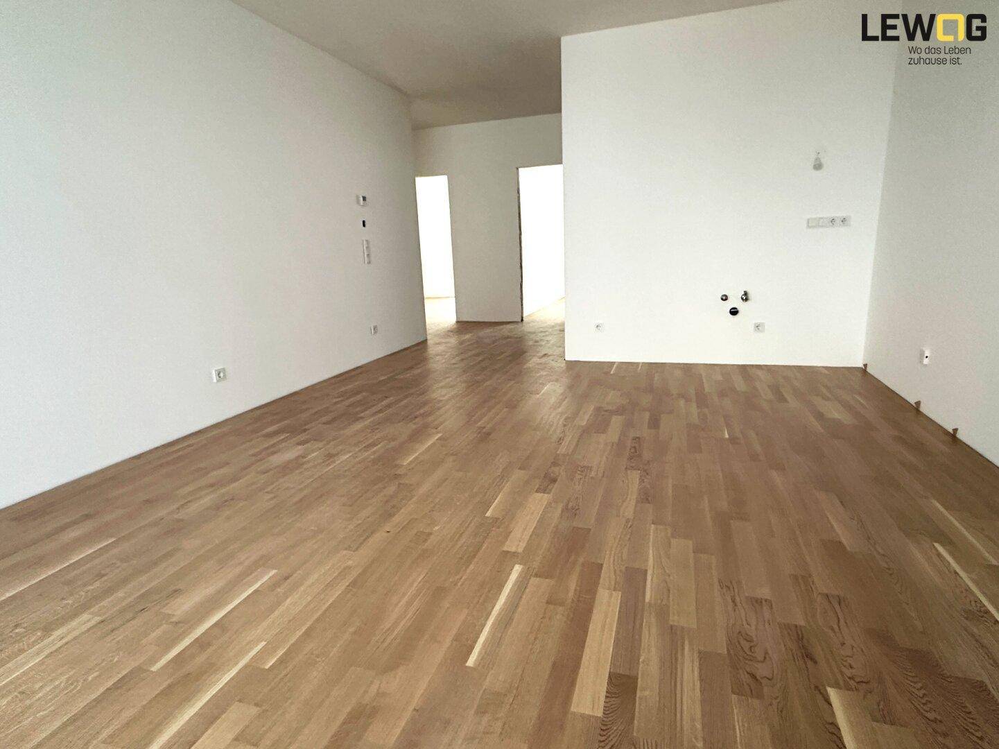 Heller, geräumiger Wohnbereich mit neuem Eichenparkett und weißen Wänden.