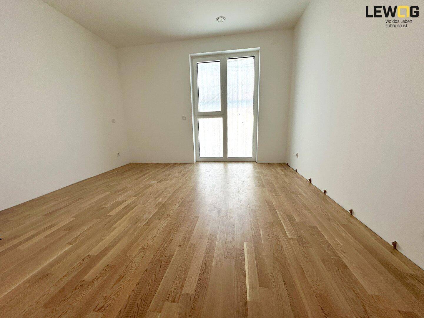 Helles Zimmer mit Eichenparkett und großem Fenster für viel Tageslicht.