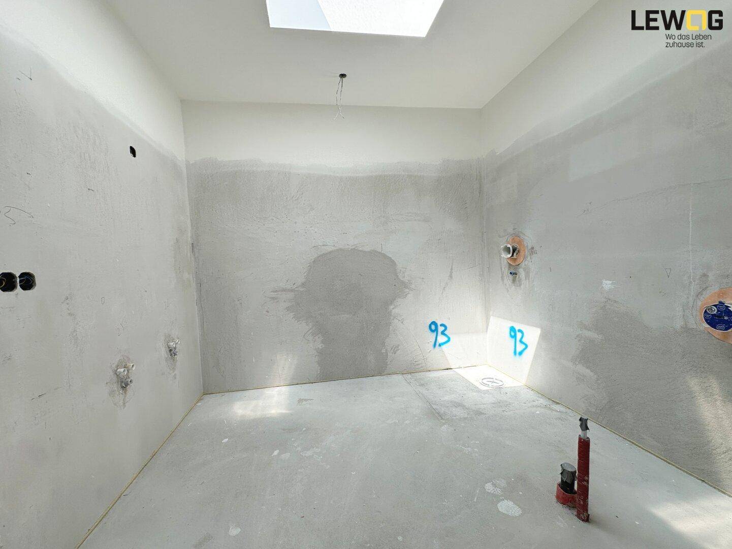 Unfertiges Badezimmer mit Rohinstallationen und einem Oberlicht für natürliches Licht.