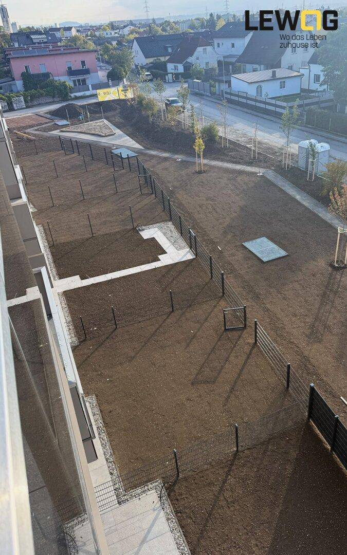 Vogelperspektive auf die Außenanlagen eines Neubaus mit vorbereiteten Gartenflächen und Wegen.