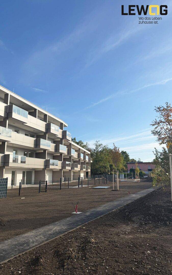 Seitenansicht eines modernen Wohngebäudes mit Balkonen und weitläufigen Außenanlagen.