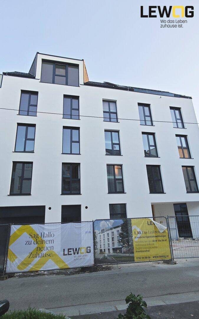 Neubau-Wohngebäude mit klarer Architektur und großen Fenstern, noch im Bau.