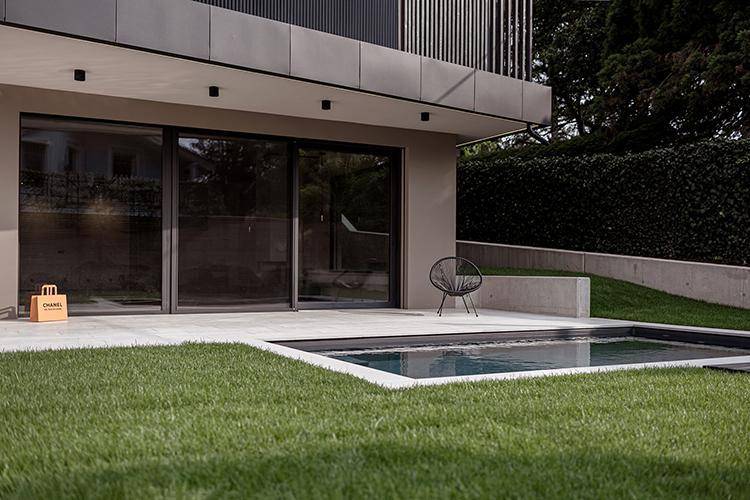 Moderner Außenbereich mit kleinem Pool, Rasenfläche und minimalistischer Terrasse.
