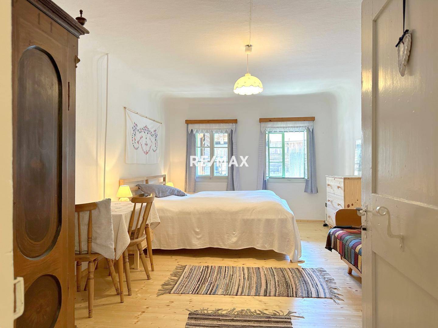Gemütliches Schlafzimmer mit Holzboden, Doppelbett und traditionellen Möbeln, hell beleuchtet.