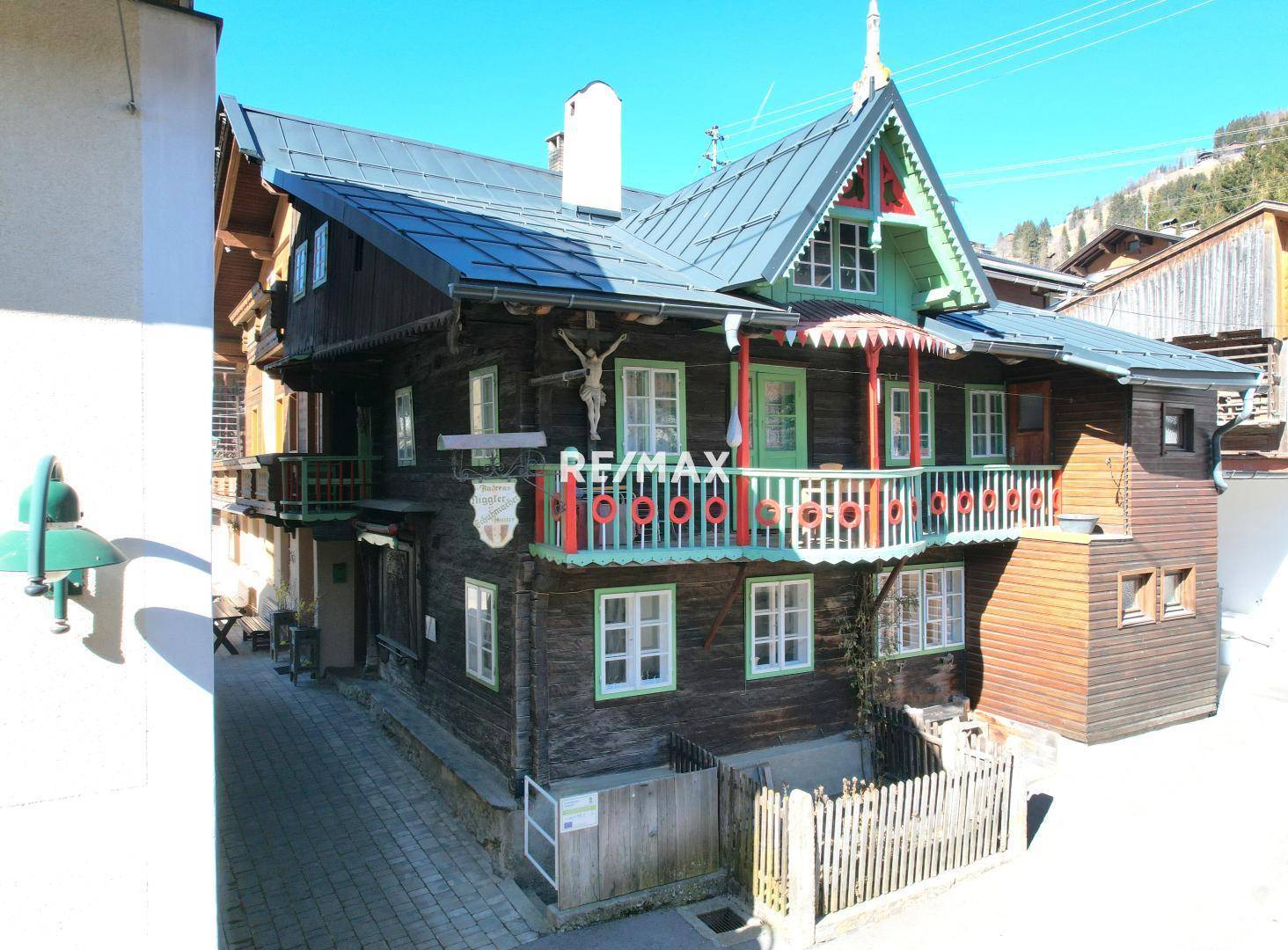 Traditionelles Holzhaus mit kunstvollem Balkon und Giebeldach in sonniger Umgebung.