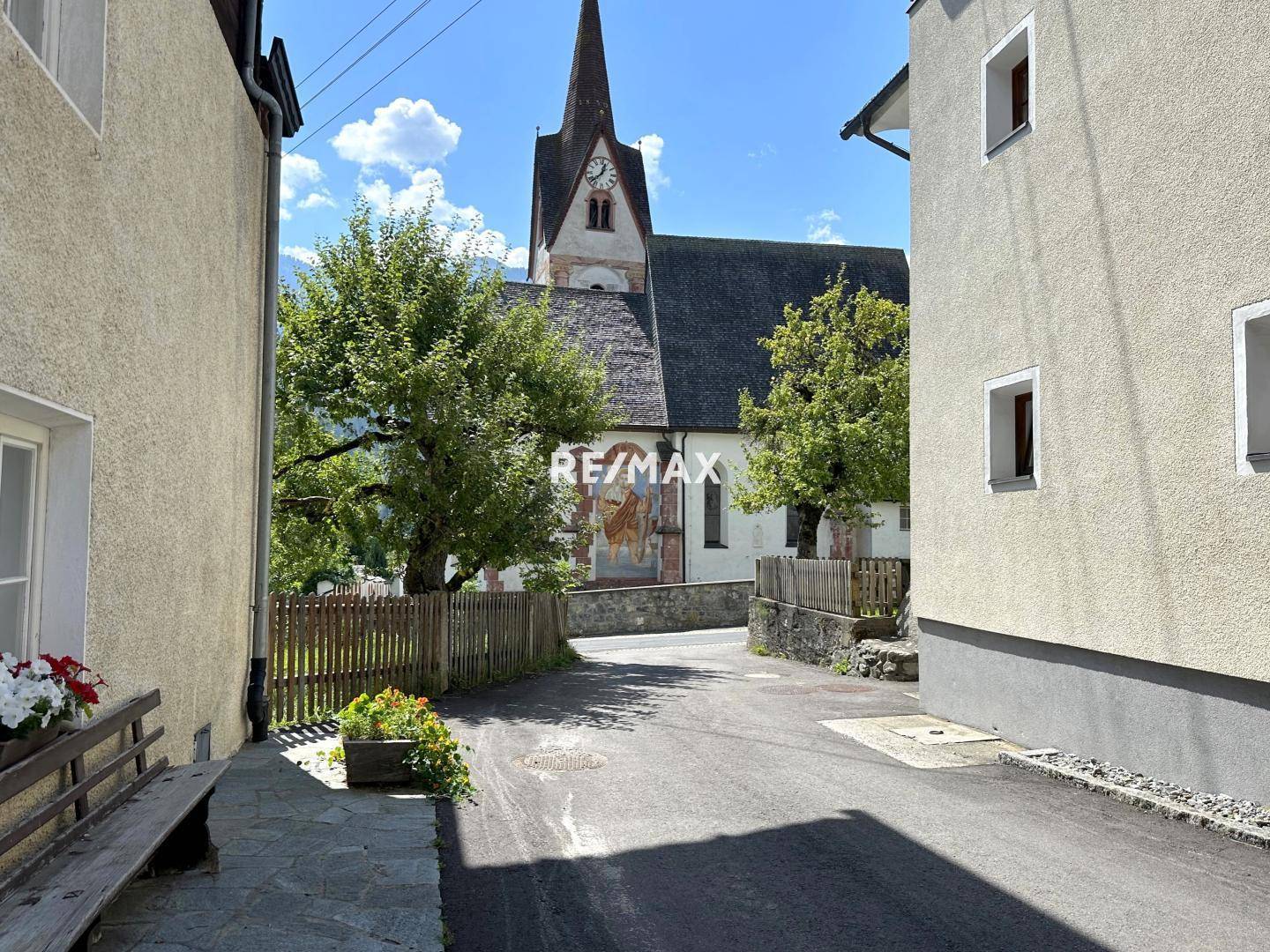 Malerische Gasse mit Blick auf eine historische Kirche unter blauem Himmel.