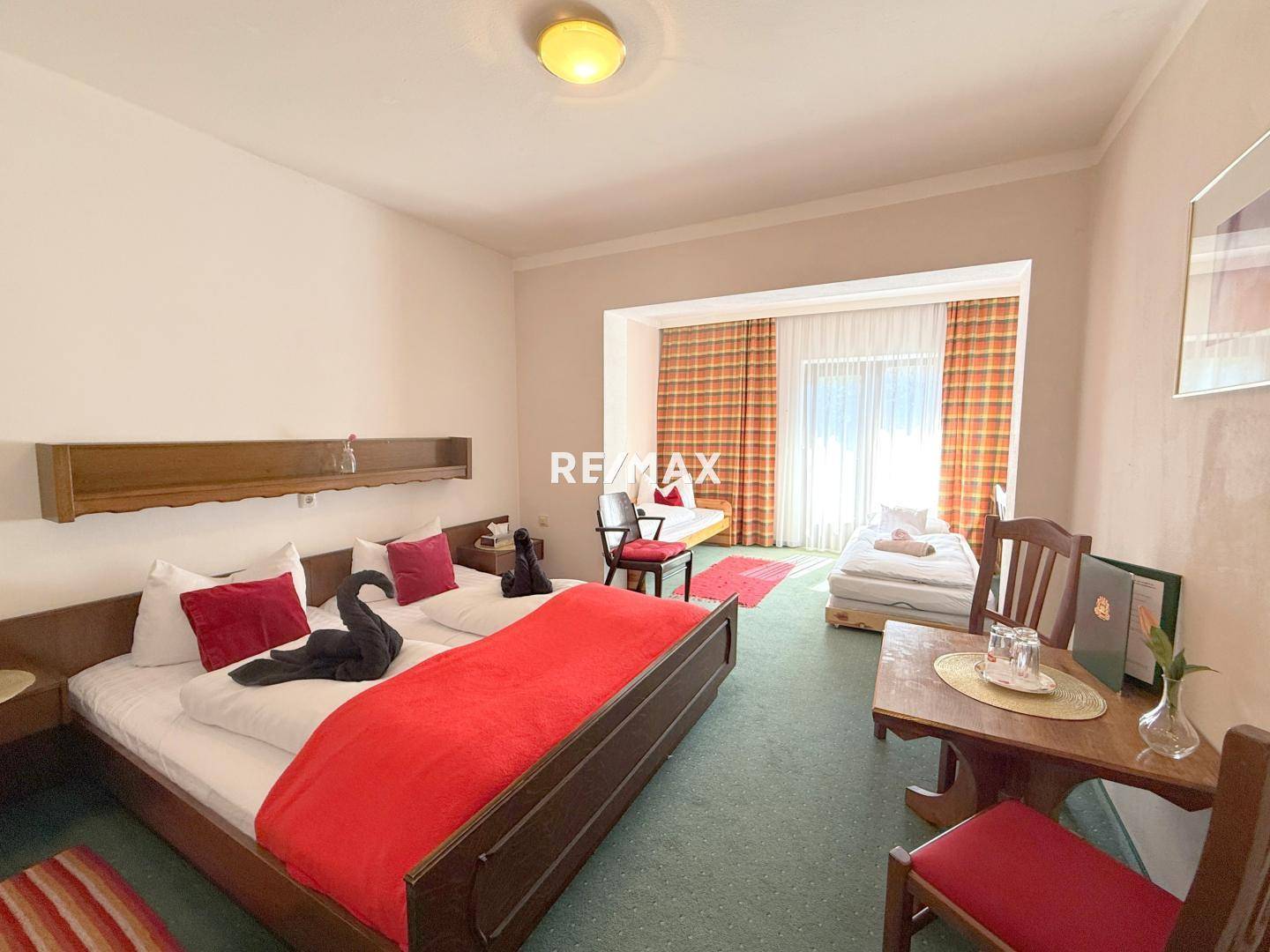 Geräumiges Schlafzimmer mit zwei Betten, grünem Teppichboden und einem schönen Blick auf die Berge.