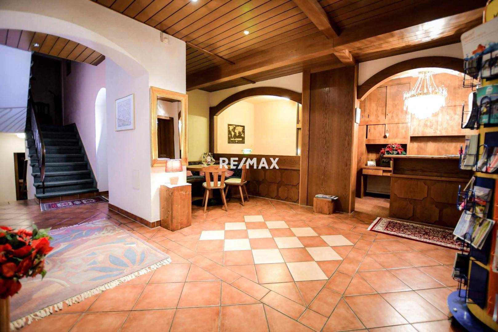 Geräumige Hotellobby mit traditionellem Design, Holzbalken und einem markanten Schachbrettmuster auf dem Fliesenboden.