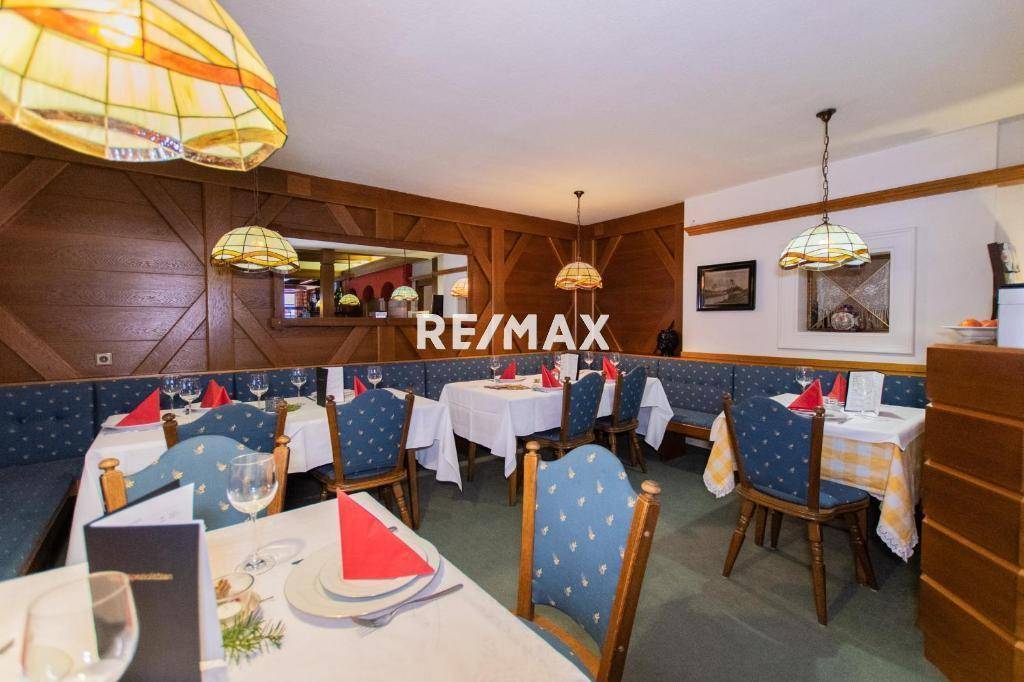 Traditioneller Restaurantbereich mit Holztäfelung, blauen Sitzbänken und liebevoll gedeckten Tischen für Gäste.