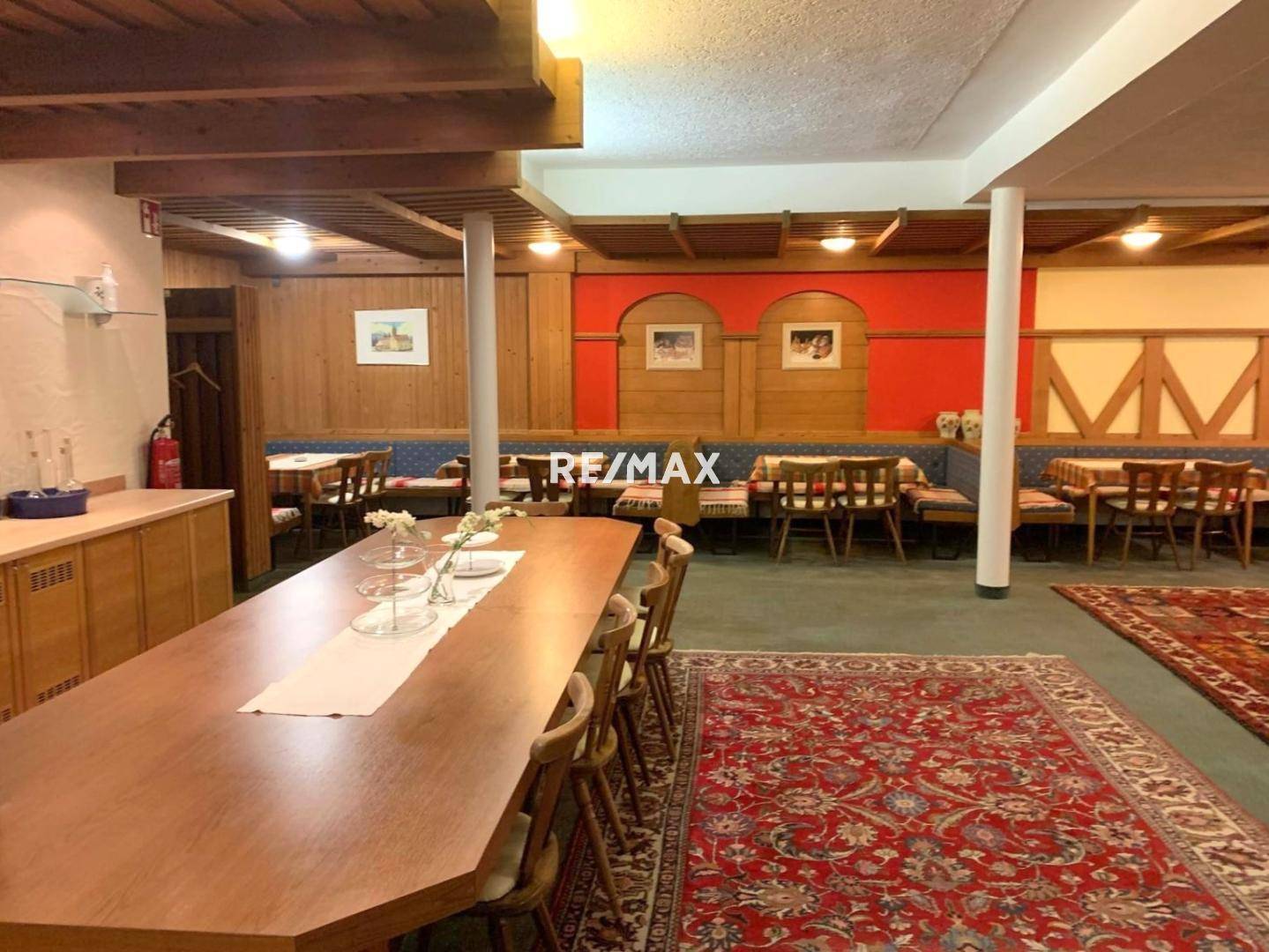 Großer Speisesaal mit langer Holztafel, Teppichboden und traditioneller Wandgestaltung, ideal für Veranstaltungen.