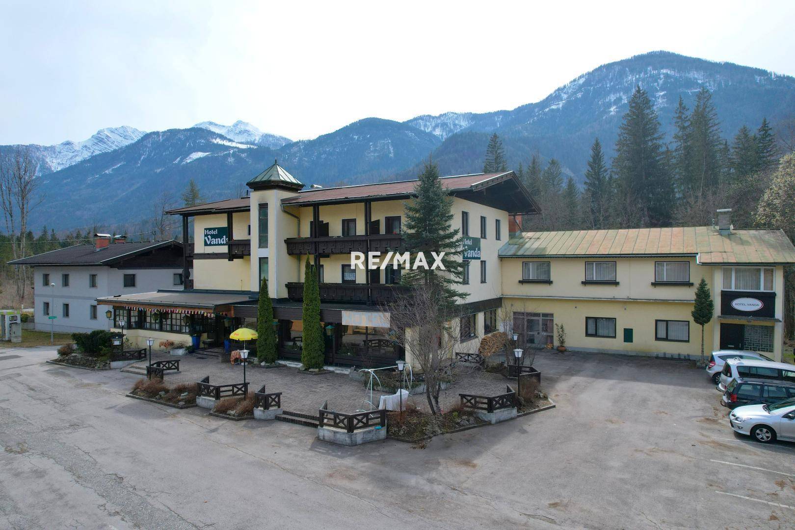 Weitläufige Hotelanlage mit traditionellem Charme, umgeben von majestätischen Bergen und einem großen Parkplatz.