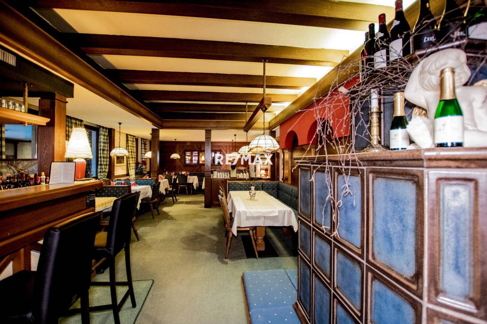 Langer Restaurantbereich mit integrierter Bar, Holzbalken und traditioneller Einrichtung, ideal für gesellige Abende.