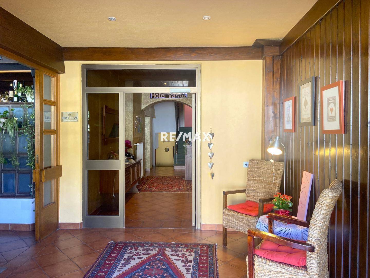 Einladender Hoteleingangsbereich mit rustikalen Holzelementen, Terrakottafliesen und gemütlichen Sitzgelegenheiten.