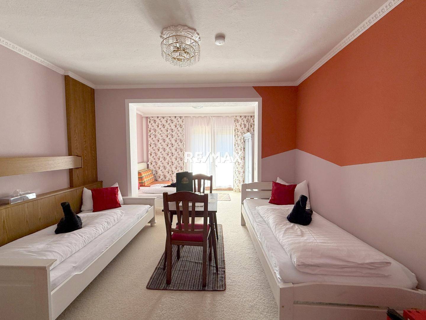 Helles Schlafzimmer mit zwei Einzelbetten, hellem Teppichboden und einer farbigen Wandgestaltung.