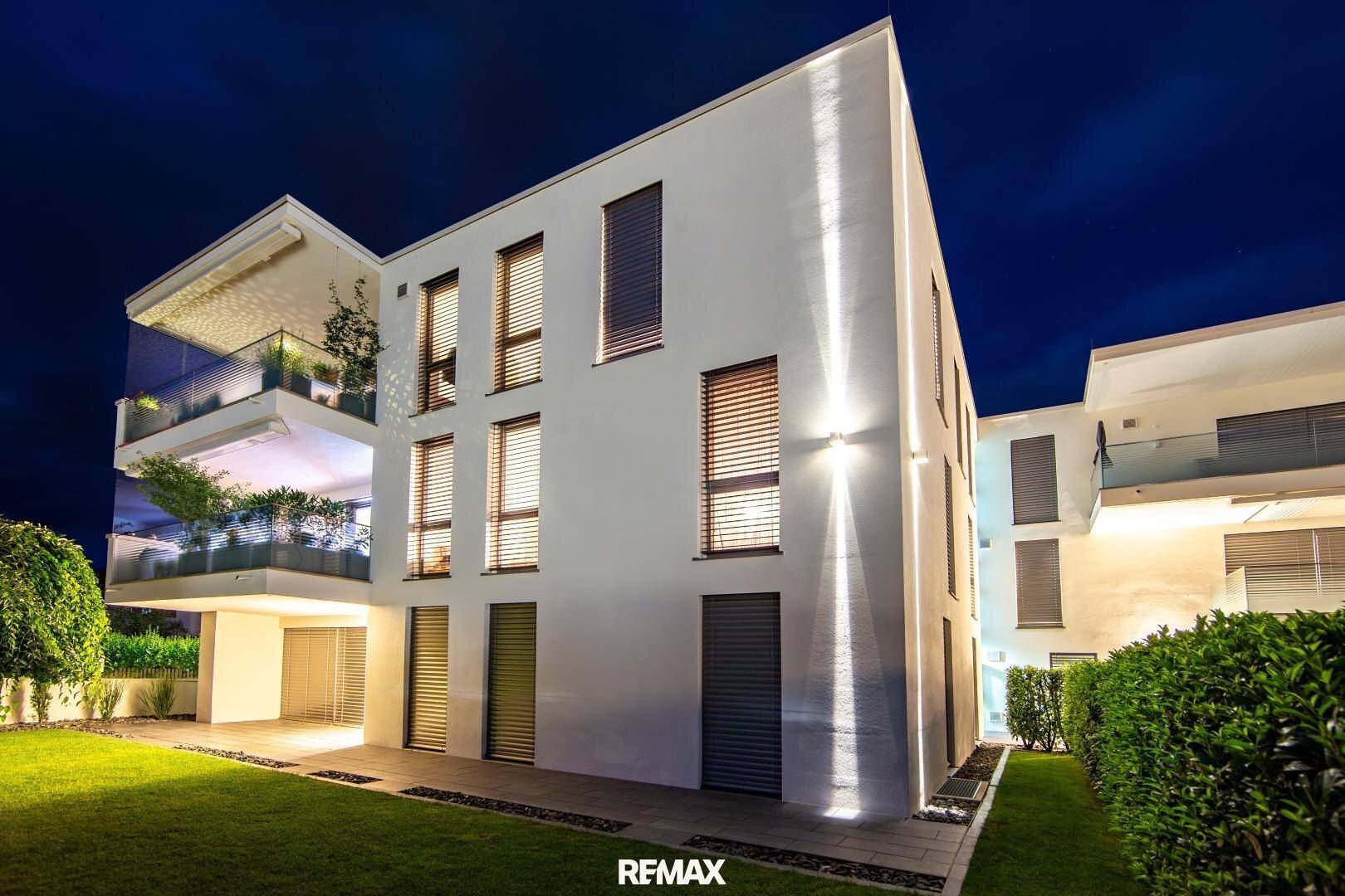 Beleuchtete moderne Fassade des Wohngebäudes bei Nacht mit stilvoller Außenbeleuchtung.