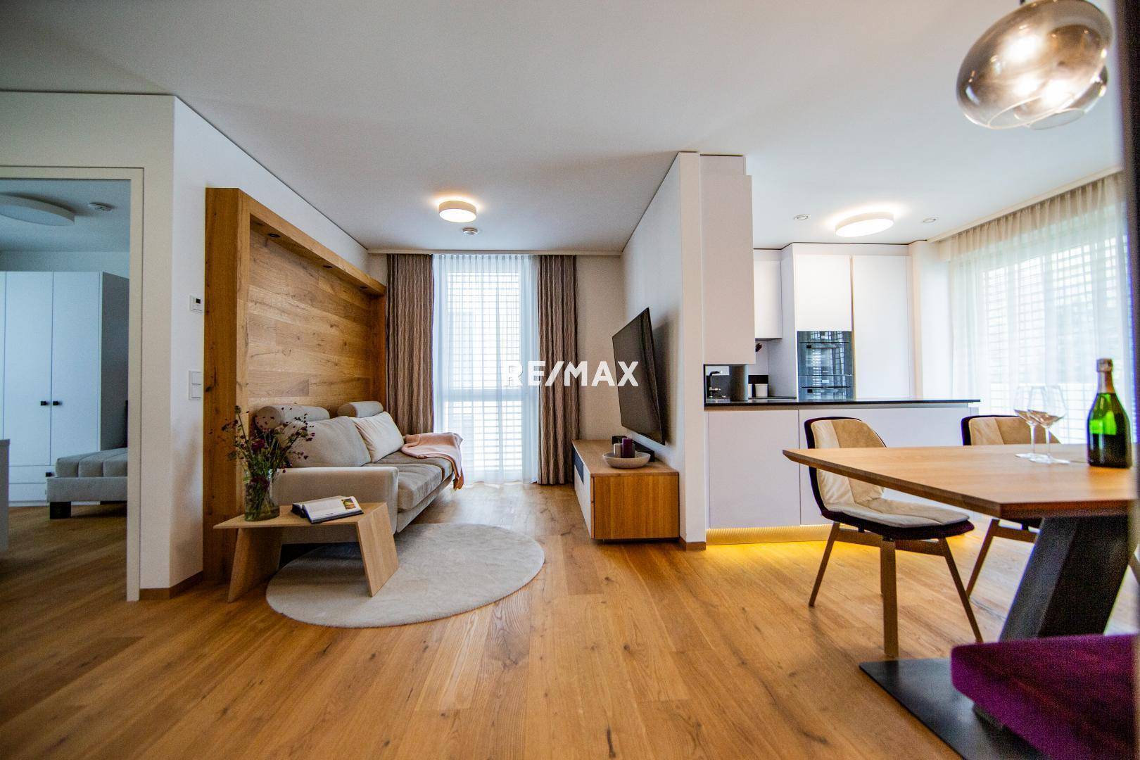 Heller Wohn-Essbereich mit Holzboden, Sofa und integrierter moderner Küche.
