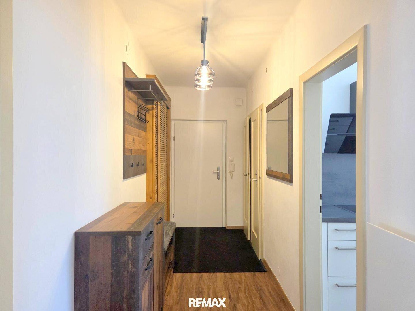 Heller Flur mit Holzmöbeln, Garderobe und Zugang zu weiteren Räumen der Wohnung.
