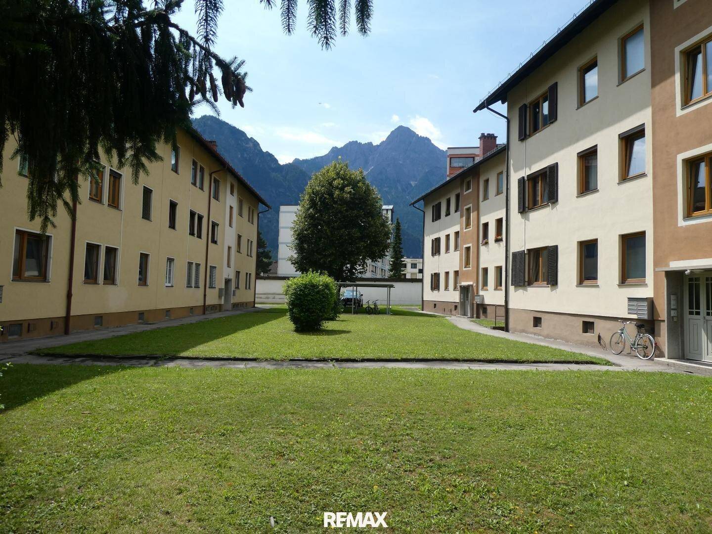 Wohnanlage mit gepflegten Grünflächen zwischen den Gebäuden und Bergblick im Hintergrund.