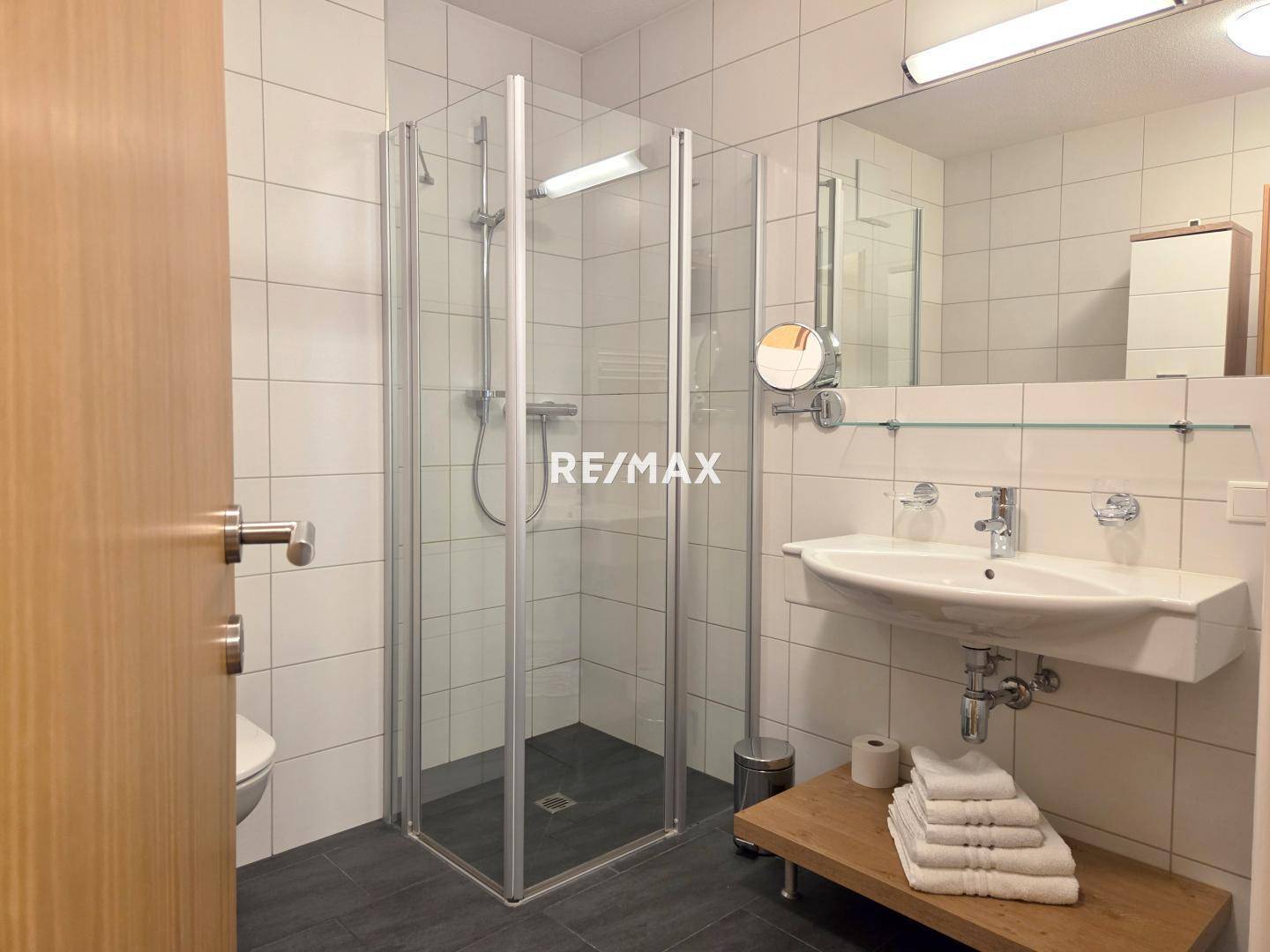 Modernes Badezimmer mit großer Duschkabine, wandhängendem WC und eleganten Fliesen, hell und funktional.