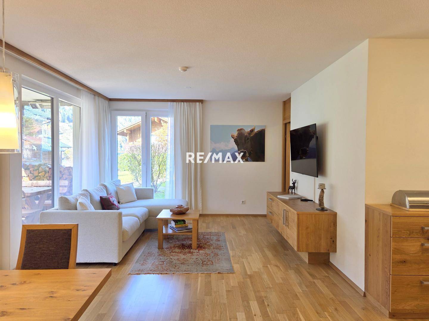 Gemütliches Wohnzimmer mit hellem Parkettboden, bequemer Couch und Zugang zur Terrasse, ideal zum Entspannen.