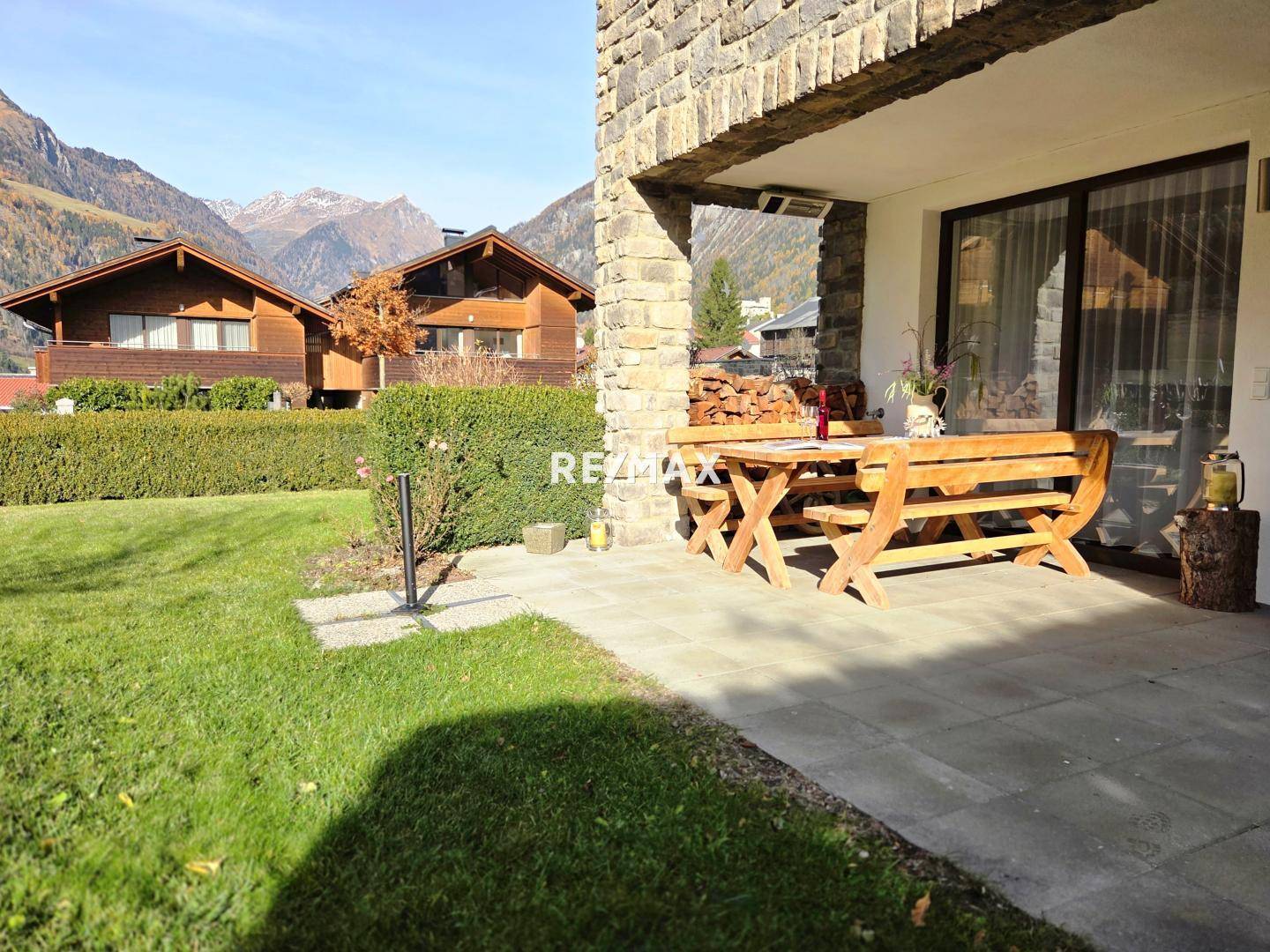 Gemütliche Terrasse mit rustikalen Holzmöbeln und Blick auf die umliegende Berglandschaft, ideal zum Entspannen.