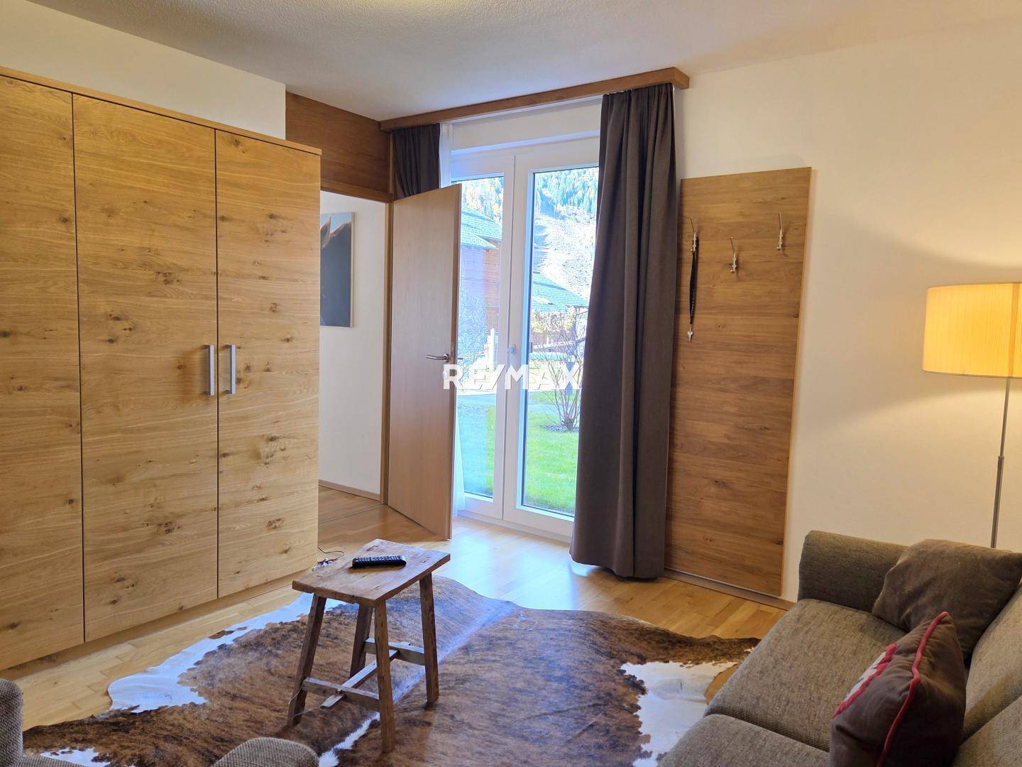 Helles Schlafzimmer mit großem Kleiderschrank, Holzboden und Zugang zum Außenbereich, gemütlich eingerichtet.