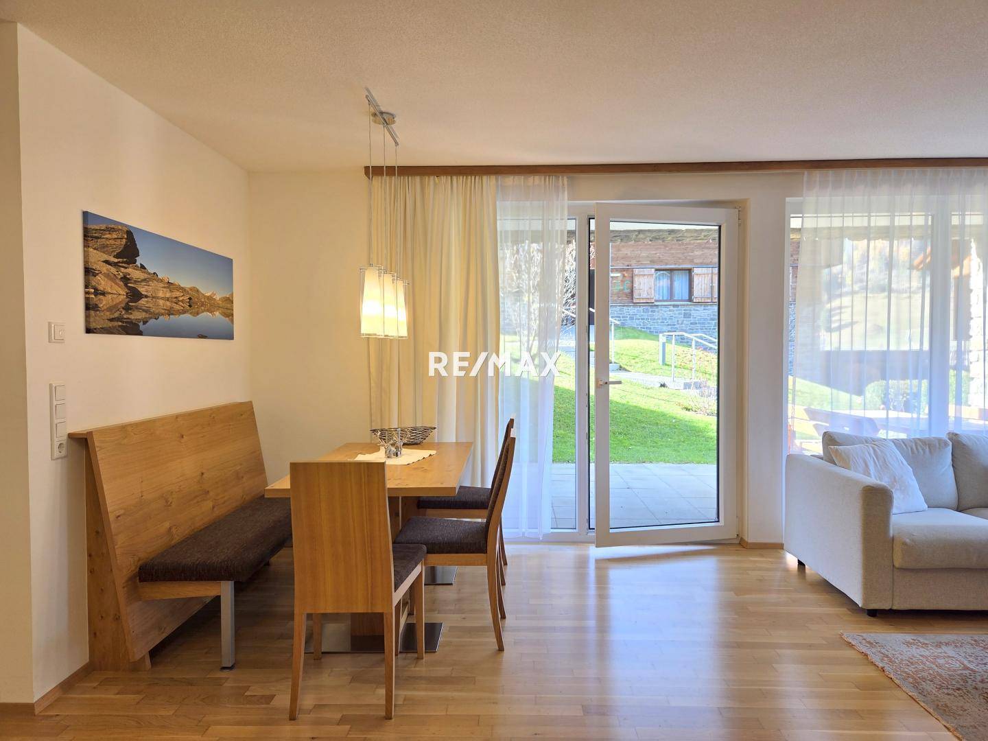 Offener Wohn- und Essbereich mit Holztisch, Sitzbank und Zugang zum Garten, perfekt für gesellige Stunden.
