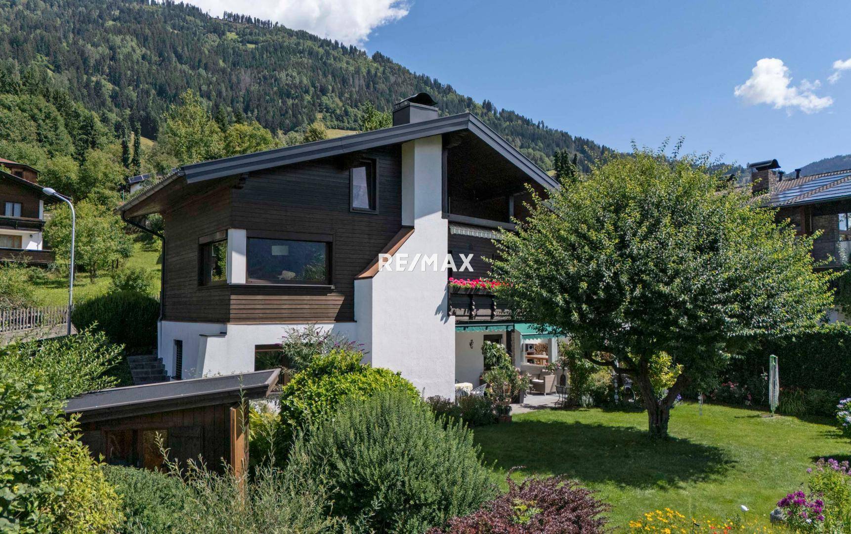Attraktives Wohnhaus mit gepflegtem Garten und grüner Umgebung unter blauem Himmel.