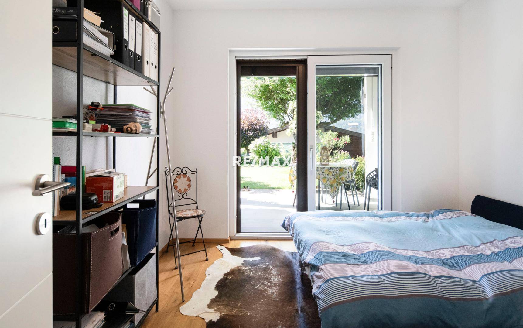 Schlafzimmer mit Holzboden und direktem Zugang zu einer Terrasse oder dem Garten.