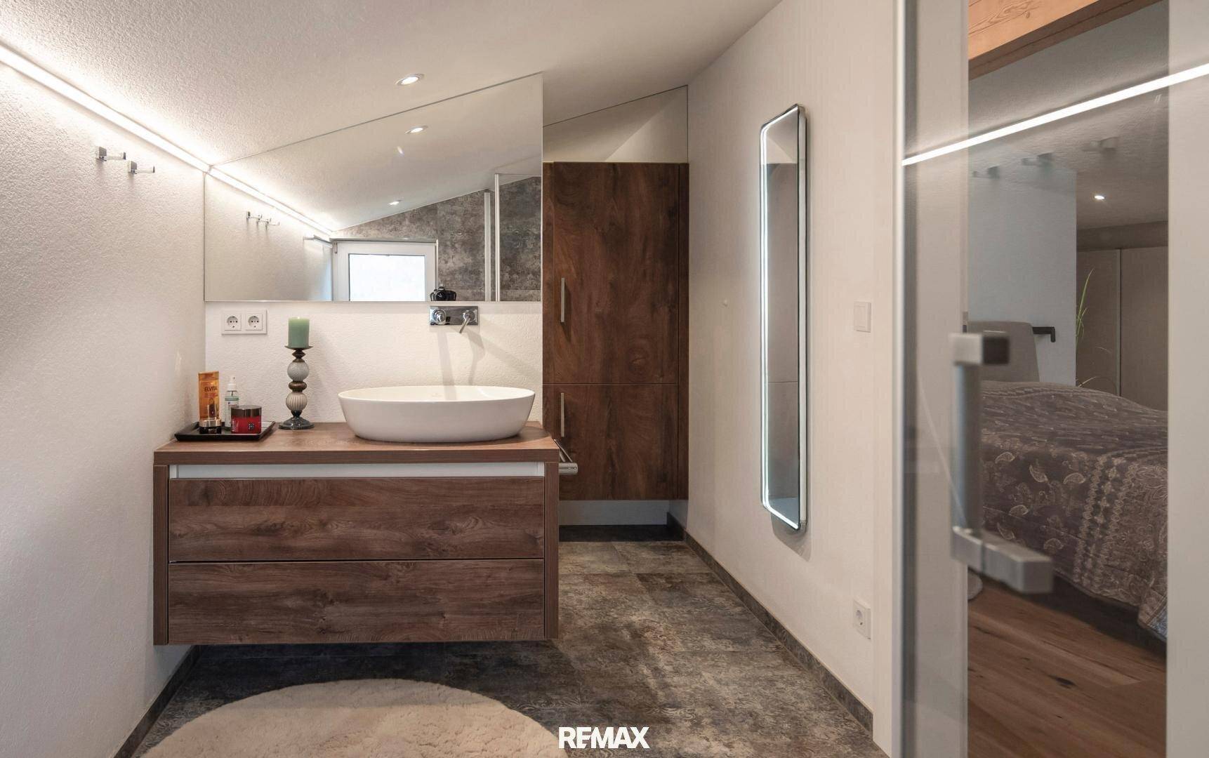 Modernes Badezimmer mit Holzwaschtisch, Aufsatzwaschbecken und großem Spiegel.