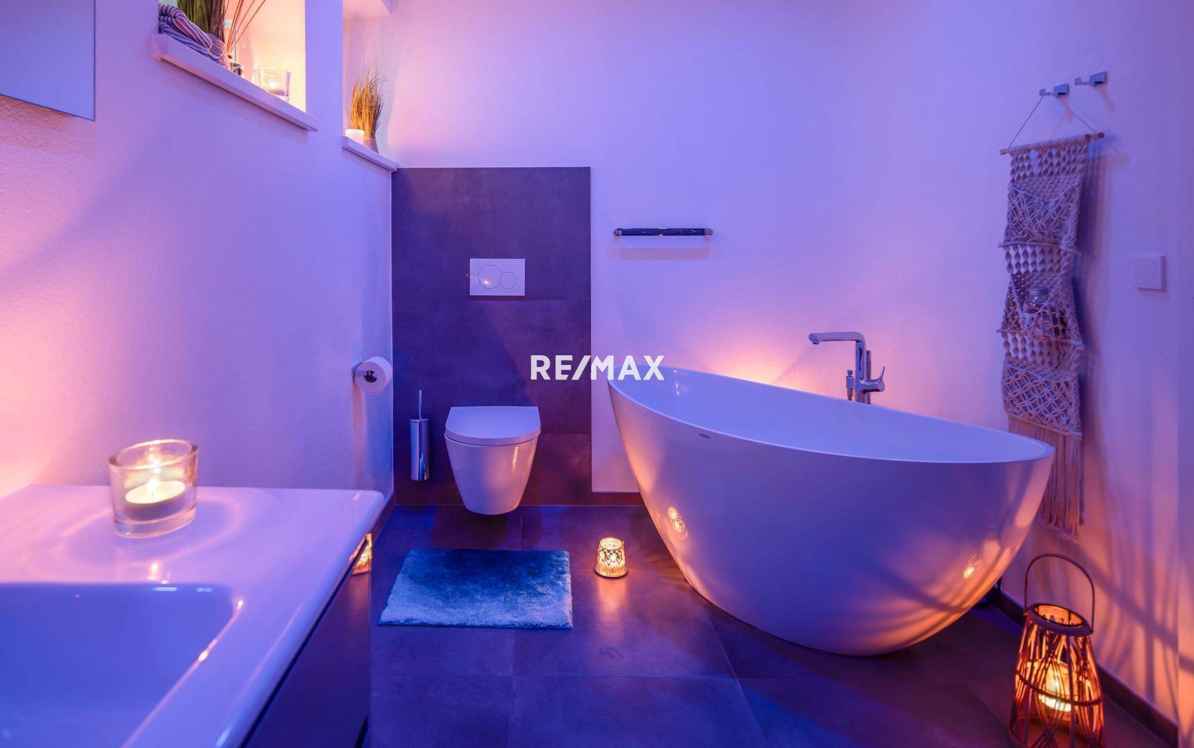 Badezimmer mit freistehender Badewanne und stimmungsvoller, farbiger Beleuchtung.