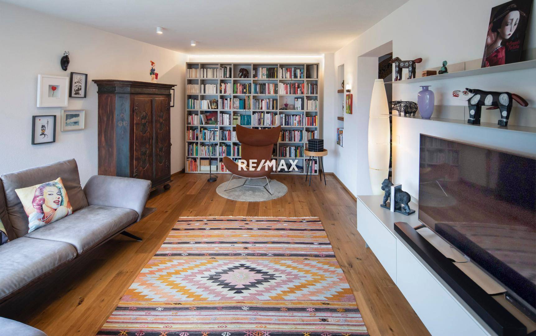 Großzügiges Wohnzimmer mit Holzboden, Bücherwand und gemütlicher Sitzecke.