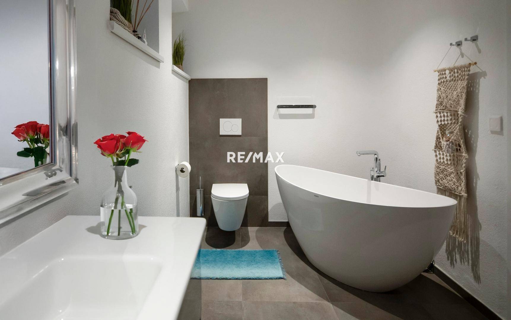 Modernes Badezimmer mit freistehender Badewanne, Wand-WC und elegantem Waschbecken.