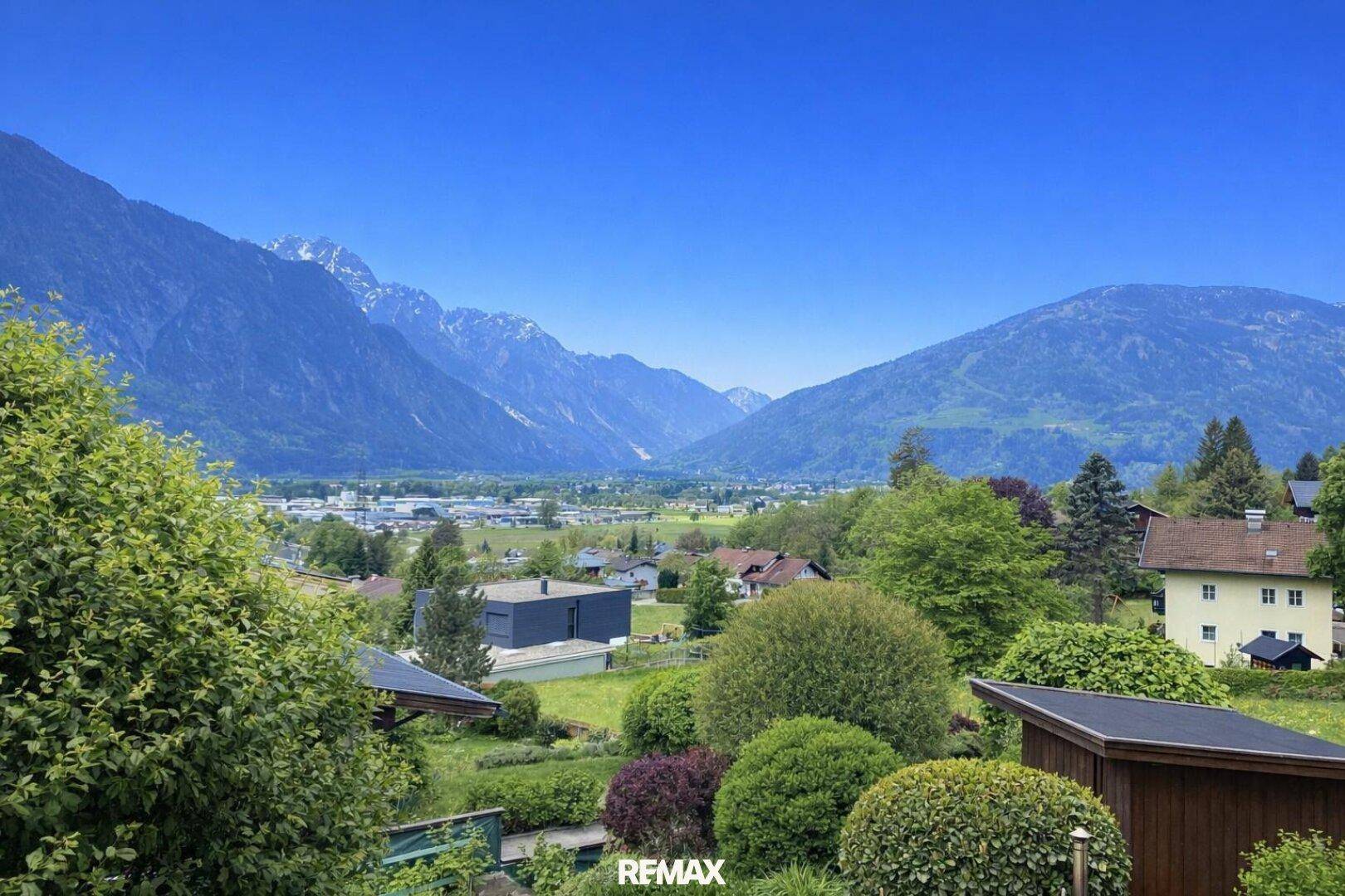 Panoramablick auf die umliegende Berglandschaft und grüne Täler mit vereinzelten Häusern.