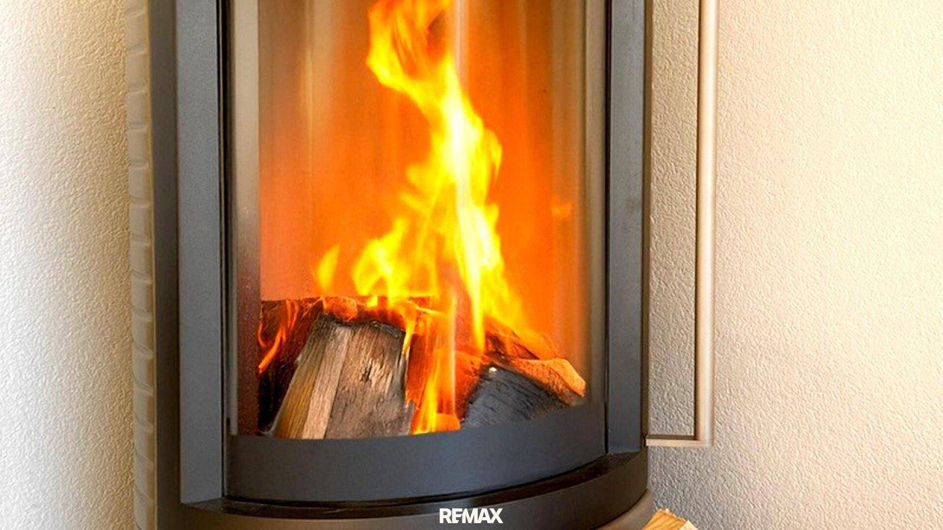 Nahaufnahme eines modernen Kaminofens mit brennendem Holz, der Wärme spendet.