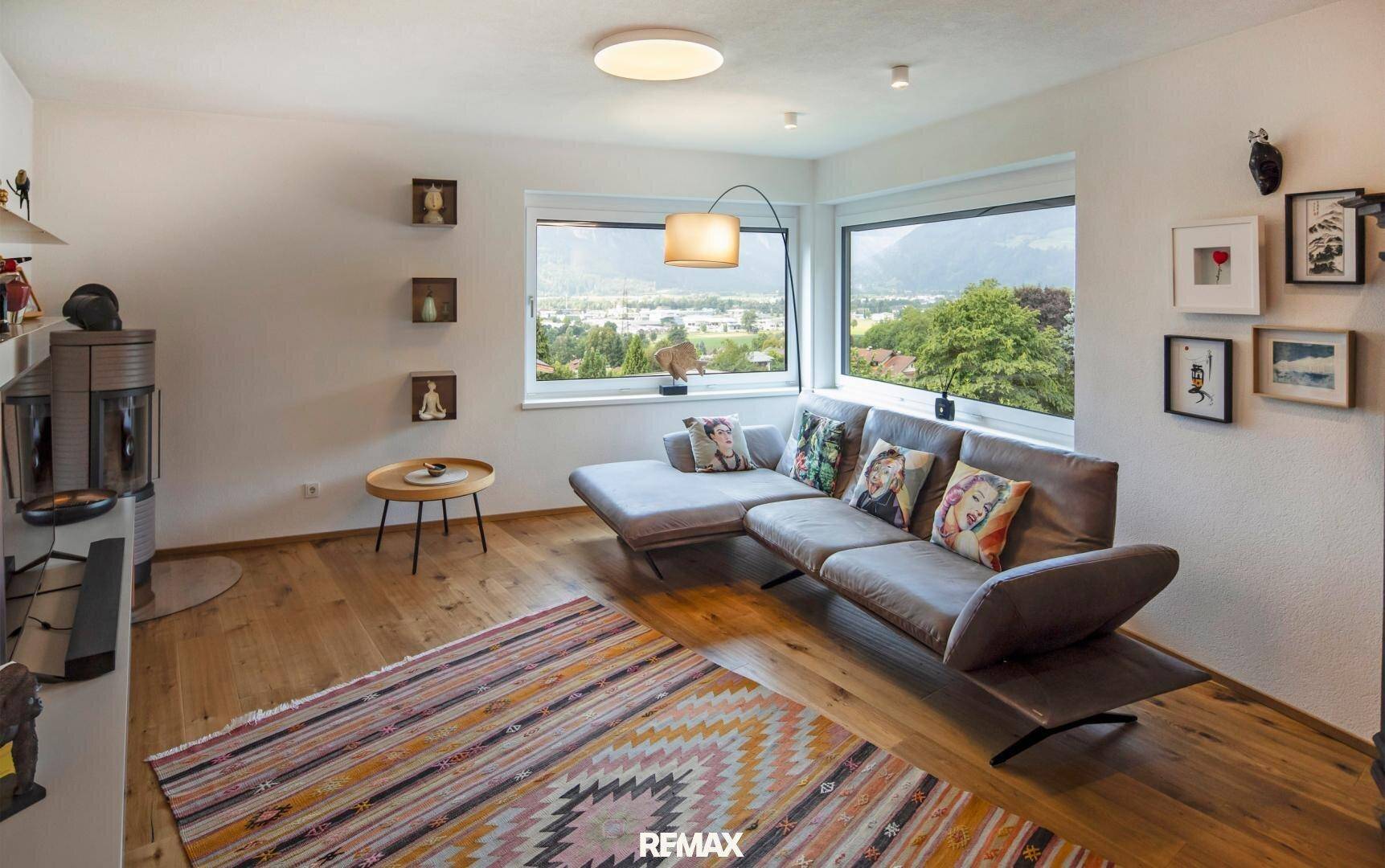 Helles Wohnzimmer mit Holzboden, bequemer Couch und weitem Blick auf die Landschaft.