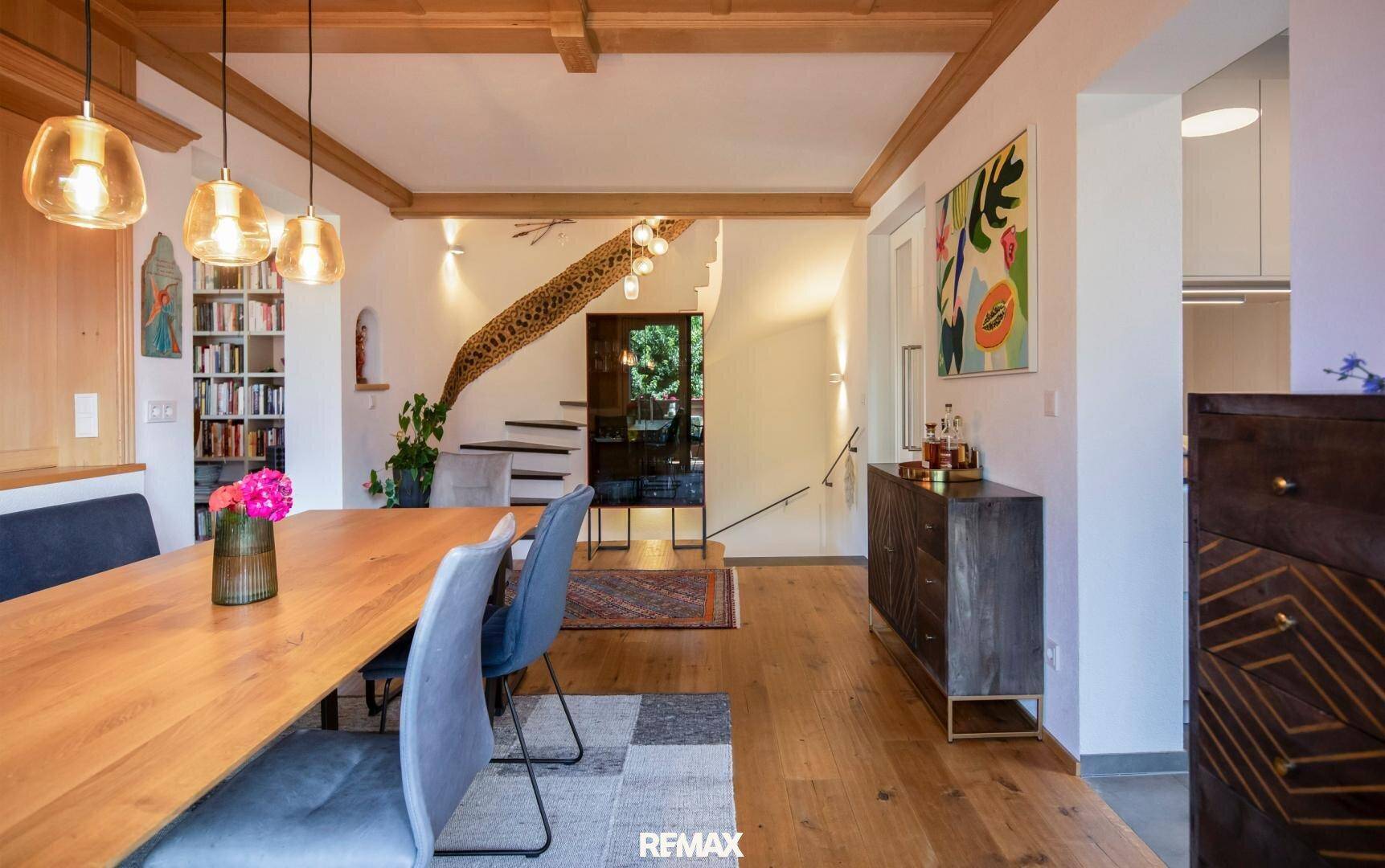 Geräumiger Essbereich mit Holzboden, Treppe und Bücherregal im Hintergrund.