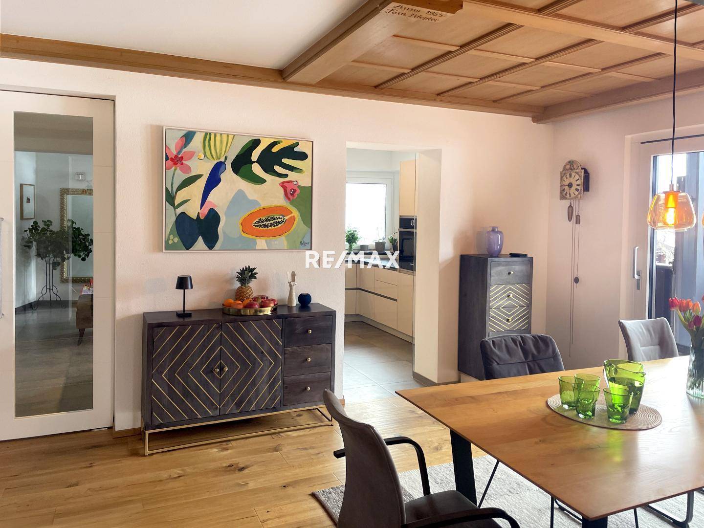 Heller Essbereich mit Holzboden, moderner Kunst und offenem Übergang zur Küche.