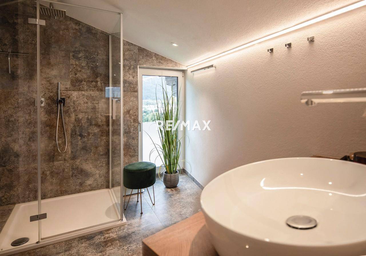 Elegantes Badezimmer mit begehbarer Dusche, modernem Waschbecken und Zugang nach draußen.