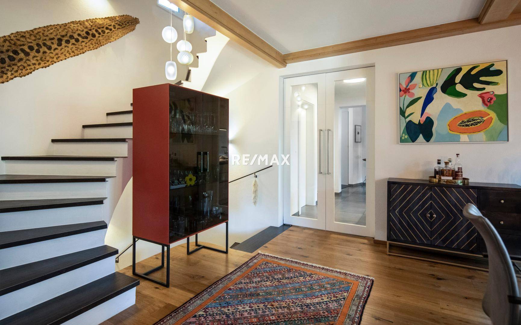 Heller Flur mit moderner Treppe, Holzboden und dekorativen Elementen.