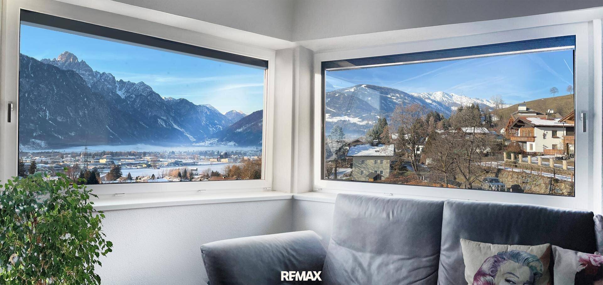 Wohnzimmer mit großen Fenstern und atemberaubendem Blick auf schneebedeckte Berge und das Tal.