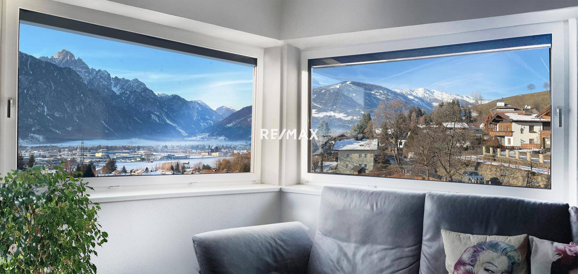 Wohnzimmer mit großen Fenstern, die einen atemberaubenden Blick auf die verschneite Berglandschaft bieten.