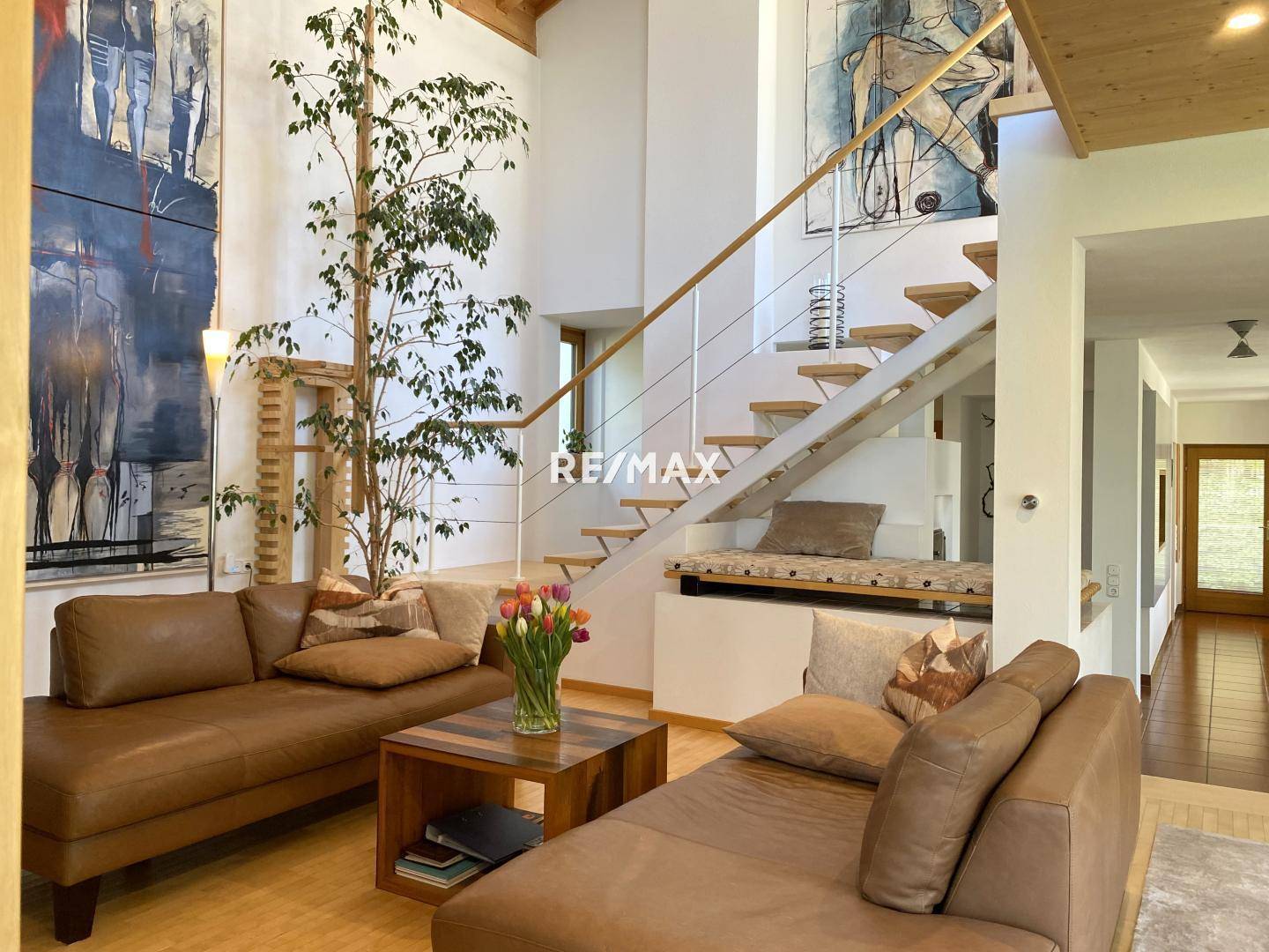 Geräumiges Wohnzimmer mit hohen Decken, Holzbalken und bequemen Ledersofas.