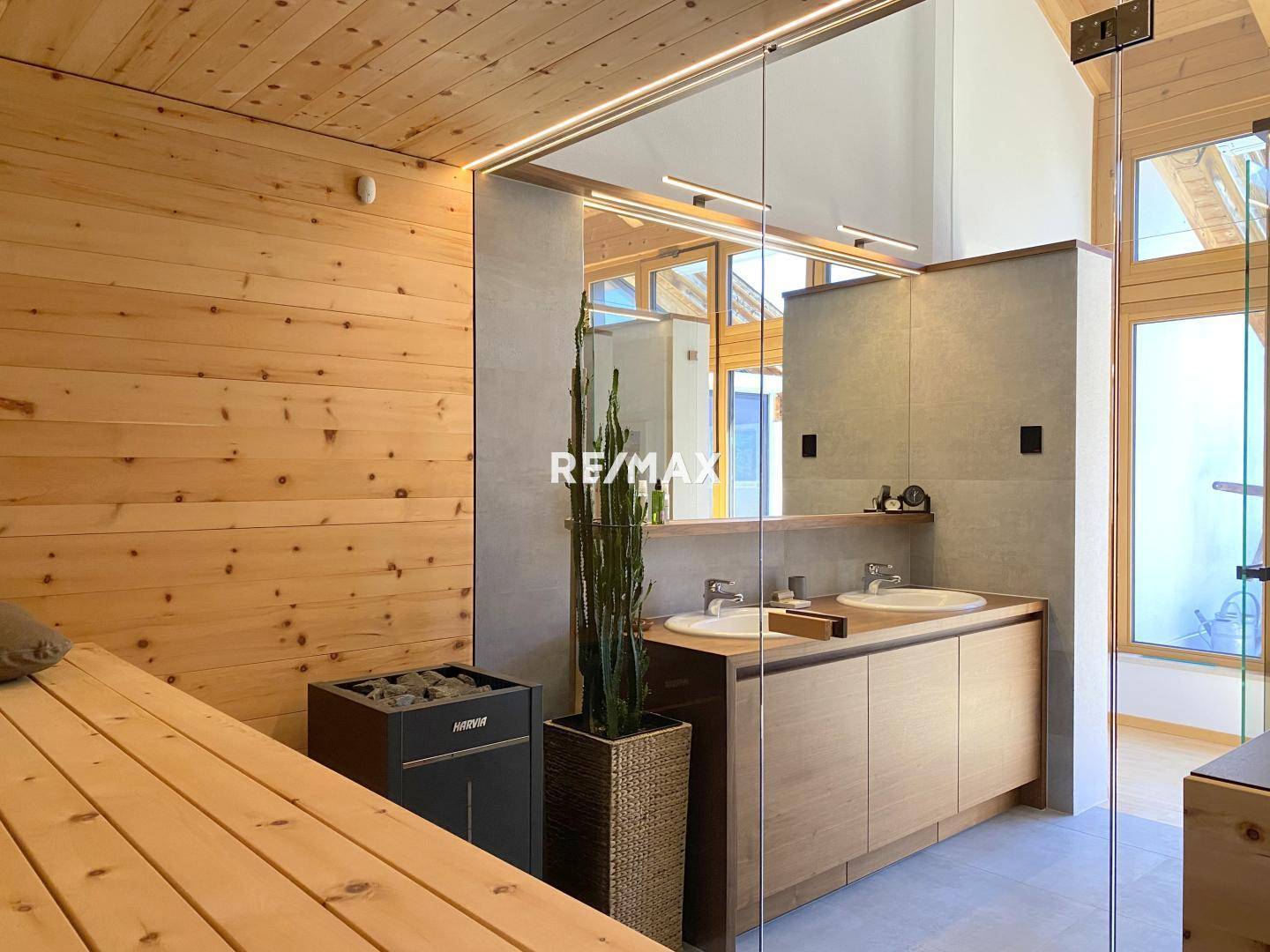 Modernes Badezimmer mit Doppelwaschbecken, großer Spiegelfläche und integrierter Sauna.