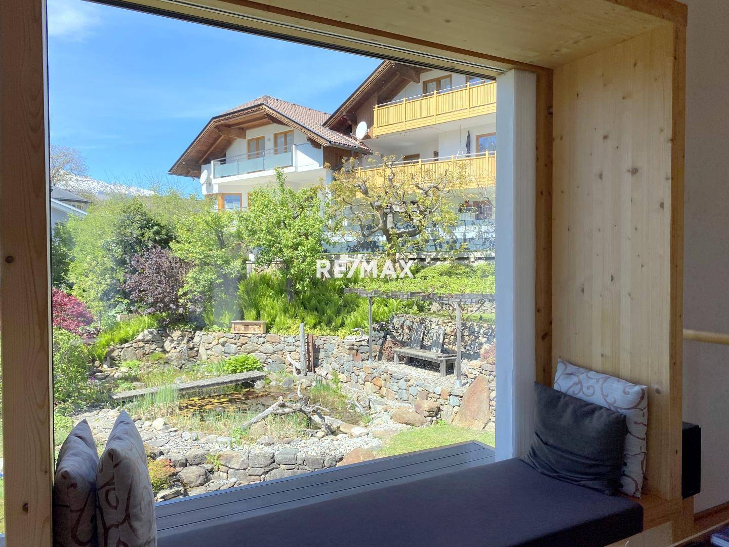 Gemütlicher Fensterplatz mit Kissen und Blick auf den gepflegten Garten und die Nachbarschaft.