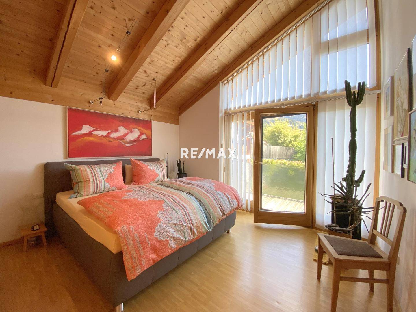 Helles Schlafzimmer mit Holzbalkendecke, großem Bett und Zugang zum Garten.
