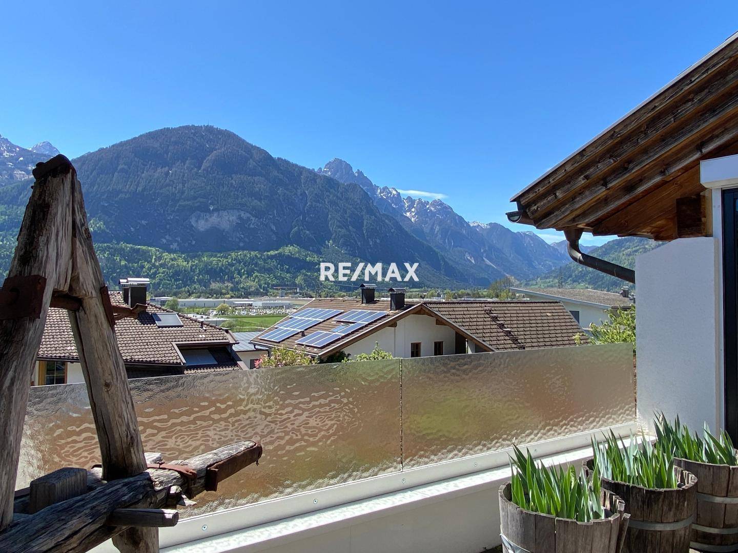 Balkon mit Milchglasbrüstung und atemberaubendem Blick auf die majestätische Bergwelt.