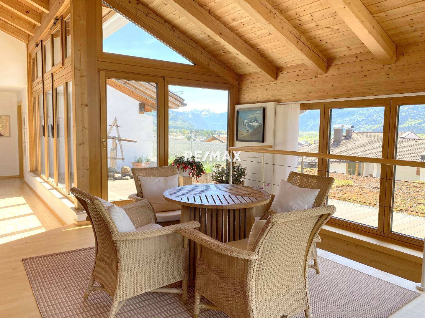 Heller Wintergarten mit Rattanmöbeln und Panoramablick auf die umliegende Landschaft.