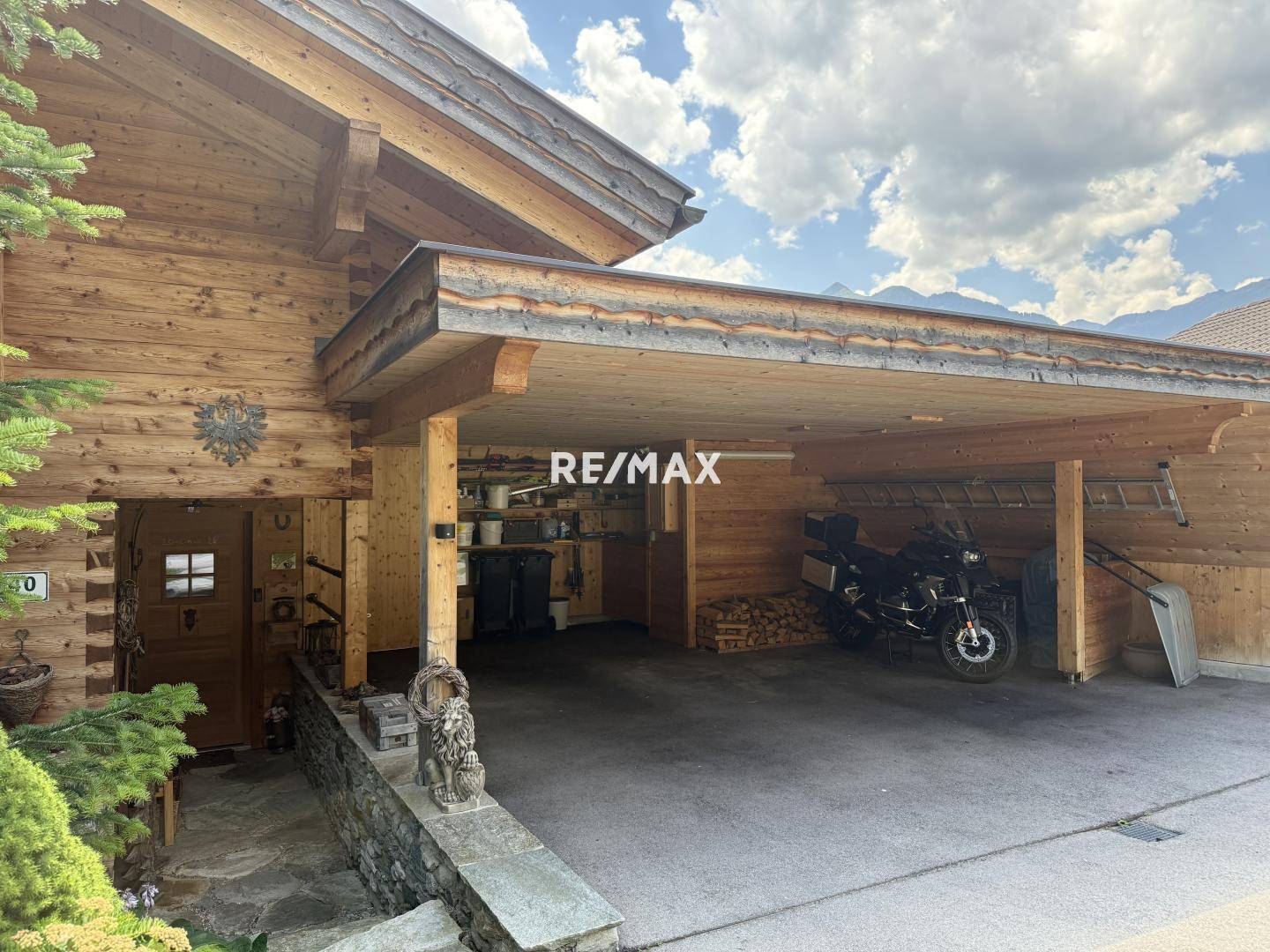 Überdachter Carport-Bereich aus Holz mit Abstellmöglichkeiten und Platz für Fahrzeuge.