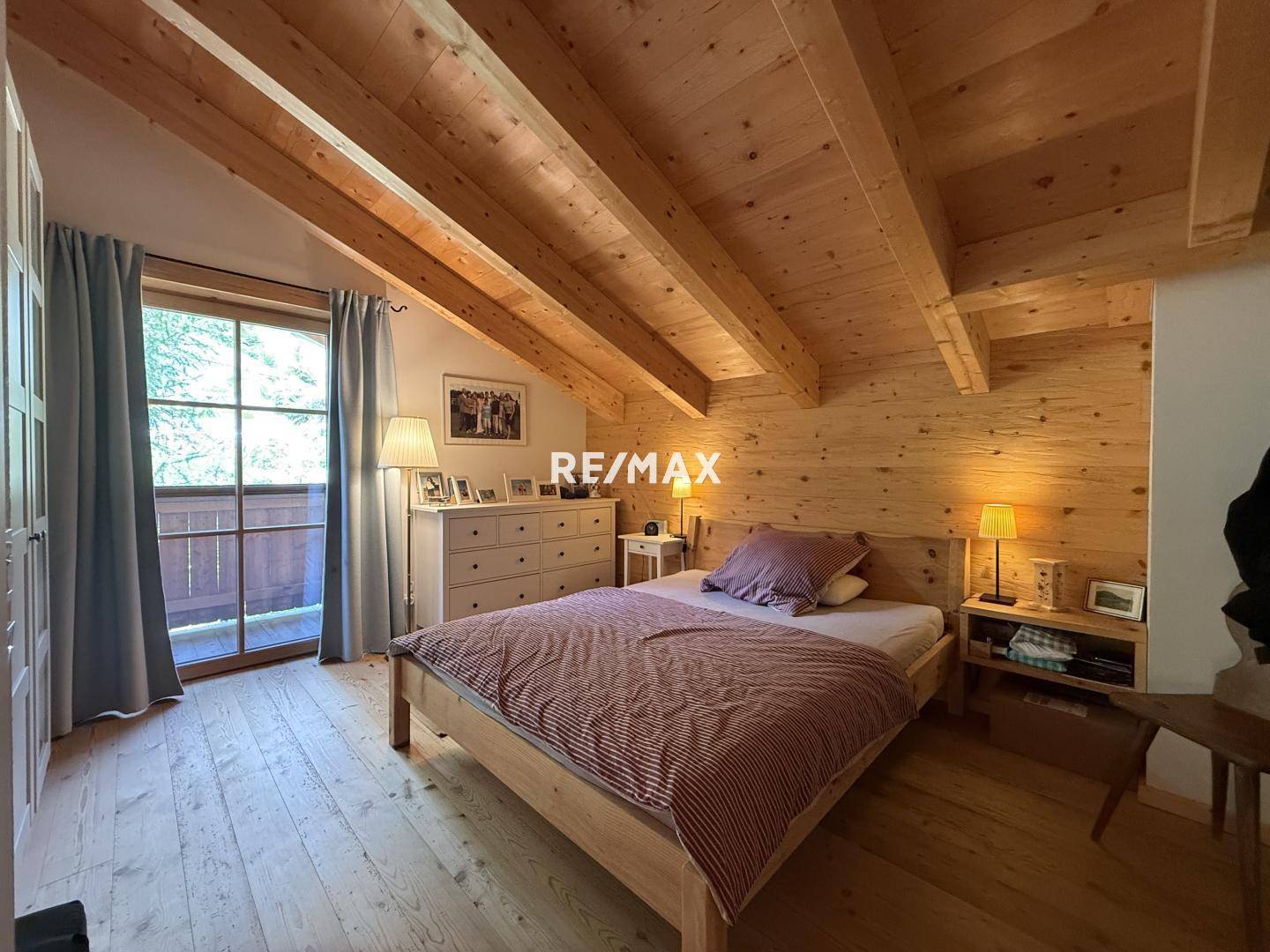 Schlafzimmer im Dachgeschoss mit Holzbalkendecke, Holzboden und Balkonzugang, hell und geräumig.